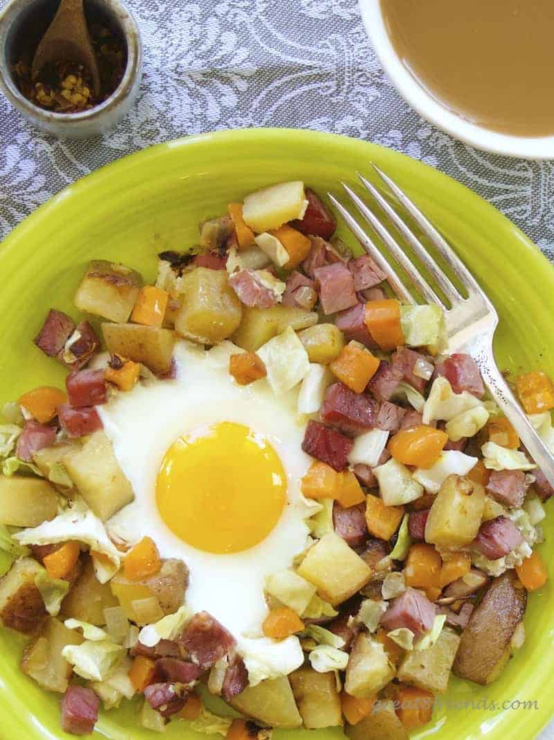 Overhead shot of hash on a plate with an egg and a cup of coffee.