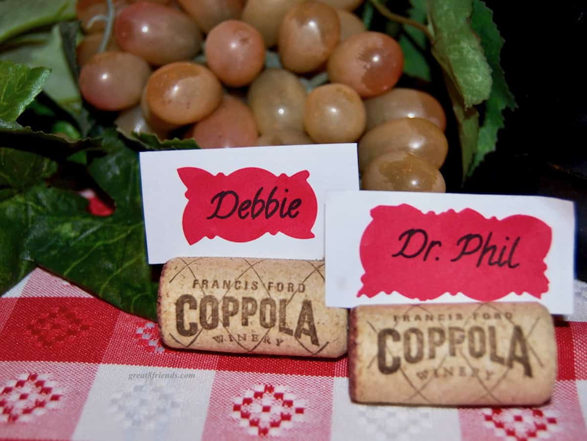 Two place cards in wine corks with grapes in the background.