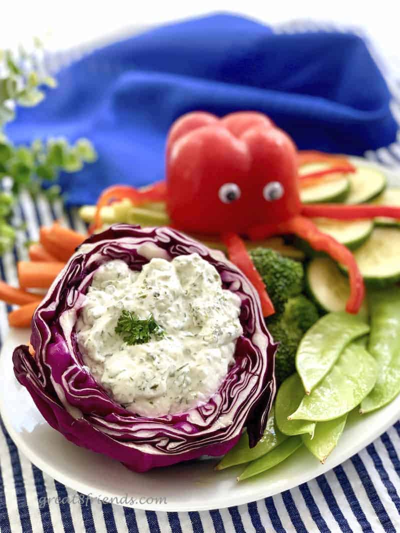 Herby Dill Dip served in a hollowed out red cabbage with a red pepper "octopus" in the background.