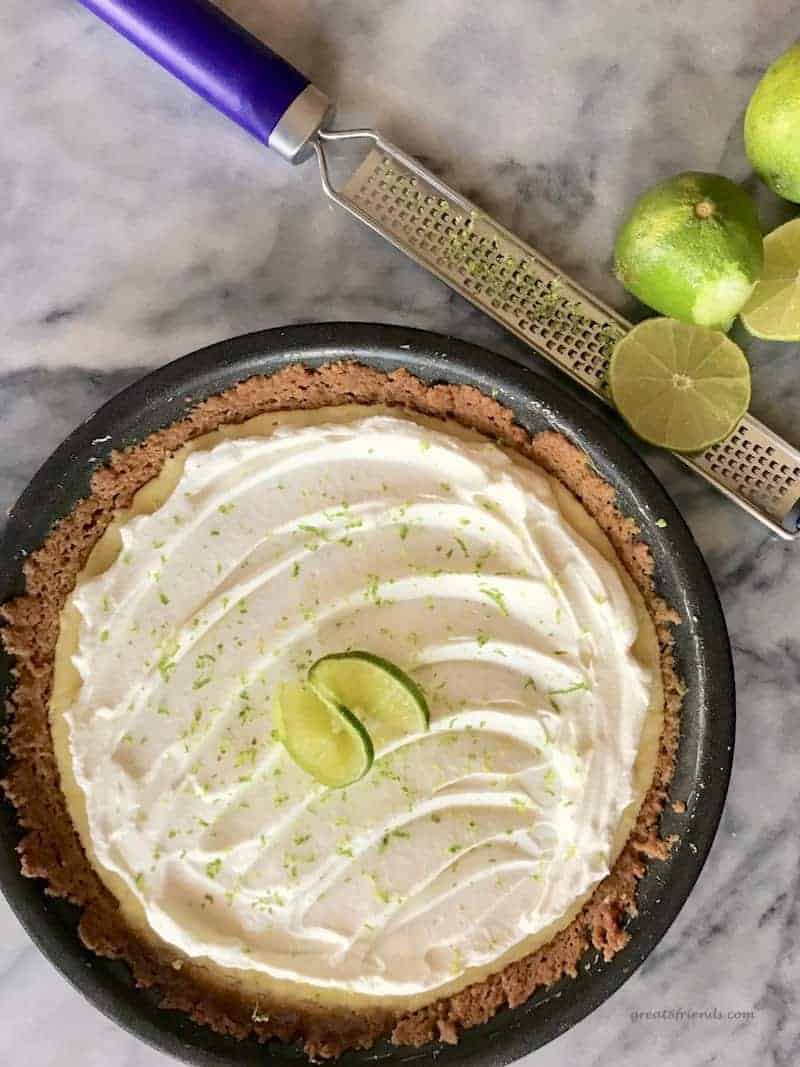 Whole key lime pie with a microplane and cut limes on the side.