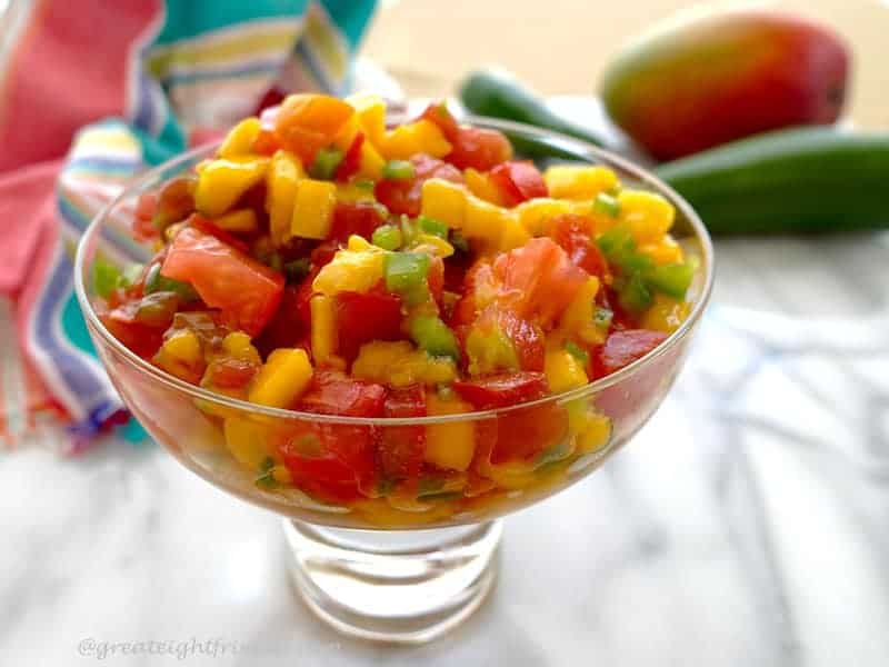 Mango Papaya Salsa in a footed glass dish on white marble.