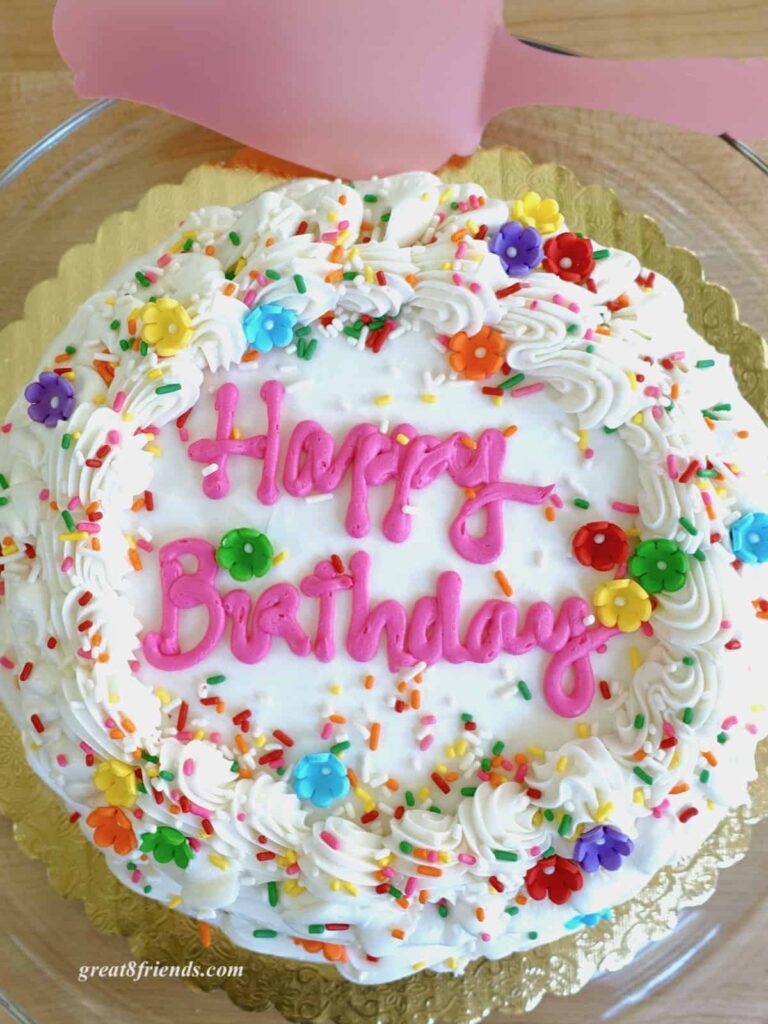 Overhead shot of white frosted cake with pink Happy Birthday writing.