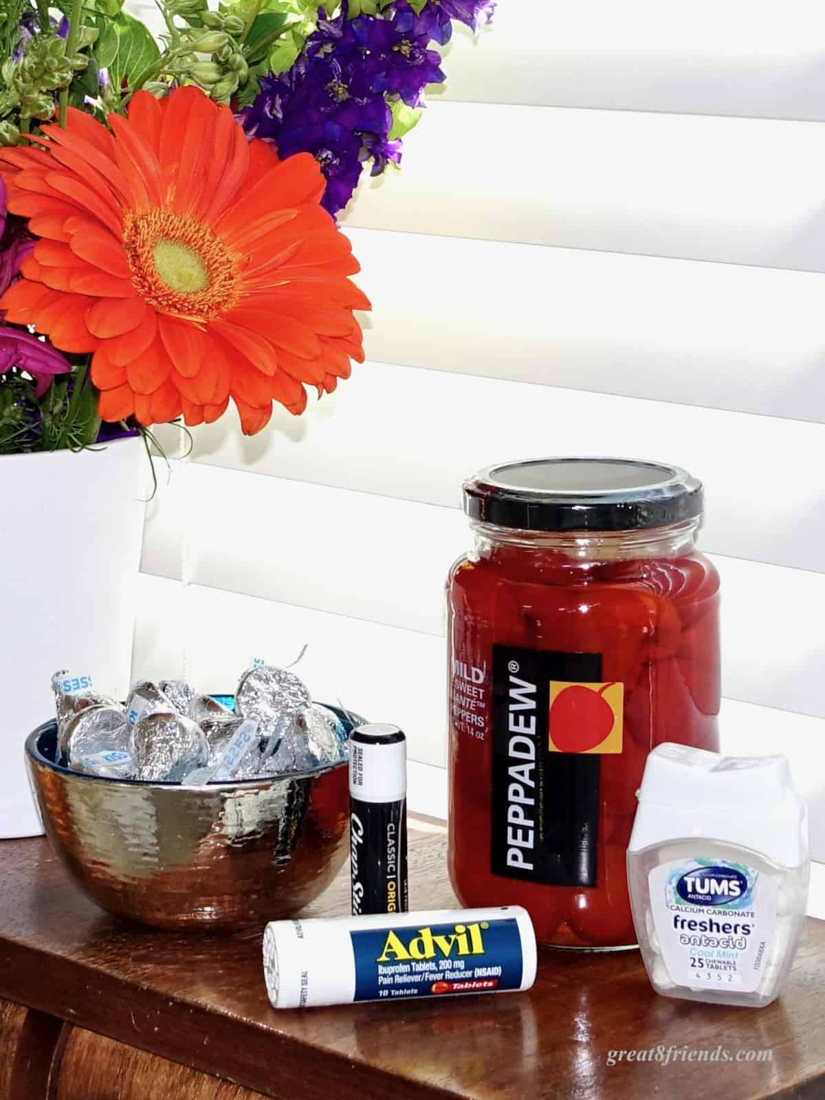 Some fresh flowers, a bowl of Hershey's kisses, Advil, ChapStick, Tums, and a jar of Peppadews.