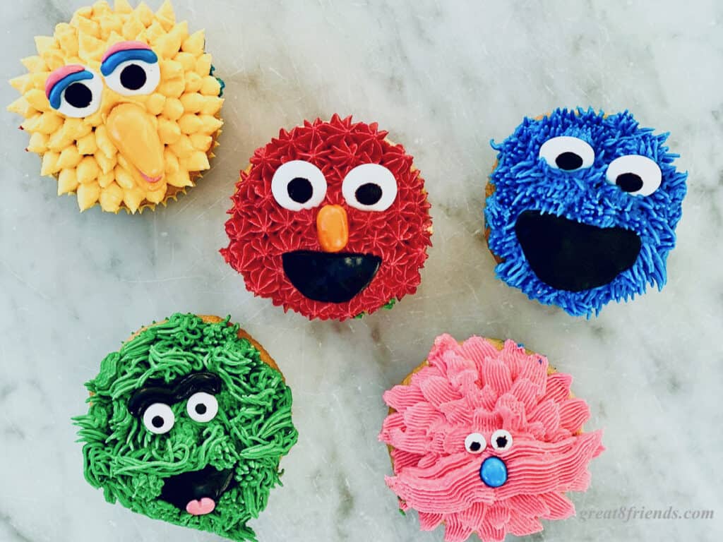 Five Sesame Street Character cupcakes, Big Bird, Elmo, Grover, Cookie Monster and a pink one.