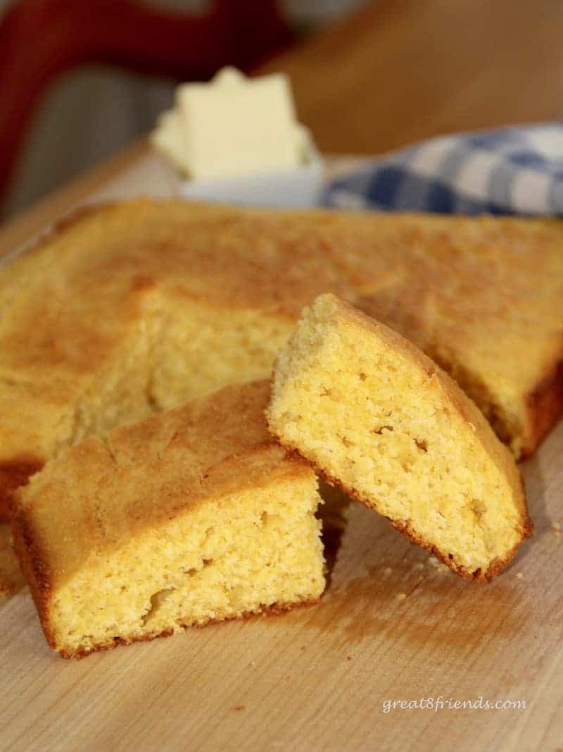 Large square golden cornbread with two pieces cut out in the foreground.