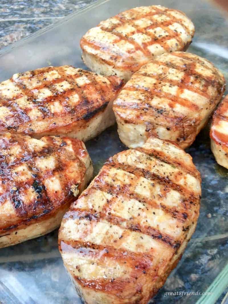 Grilled individual pork chops in a glass pan.