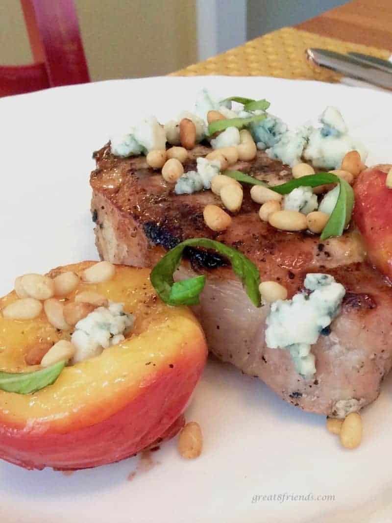 This delicious grilled pork chop paired with a grilled nectarine is a perfect duo. Topped with a rub of basil and a sprinkle of blue cheese and pine nuts, makes this is a perfect recipe.