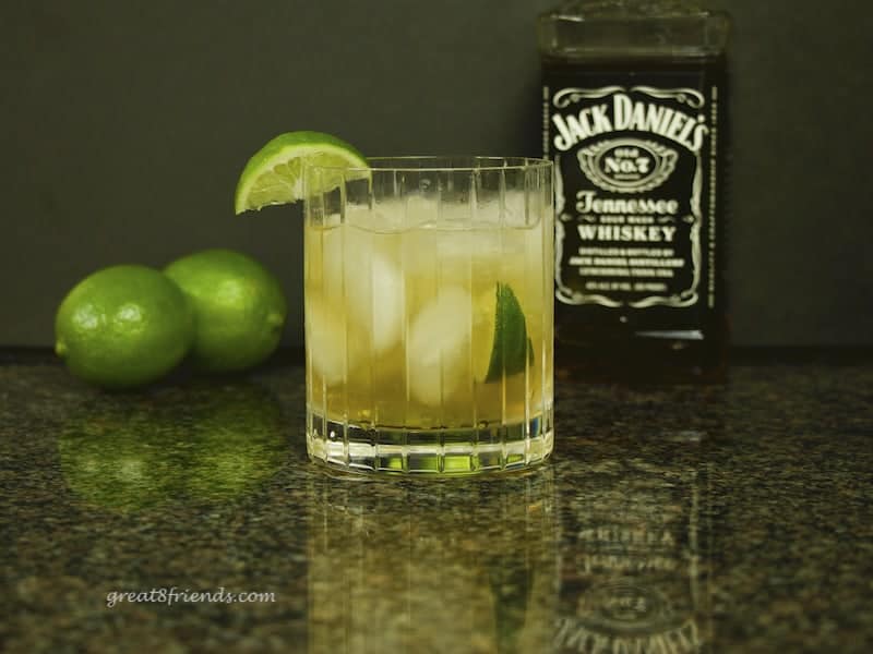 Whiskey Swirl Cocktail with Jack Daniels and limes in the background.