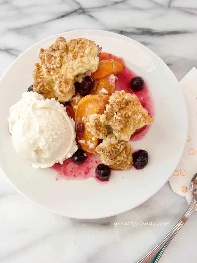 Apricot Blueberry Cobbler on a plate with a scoop of ice cream.