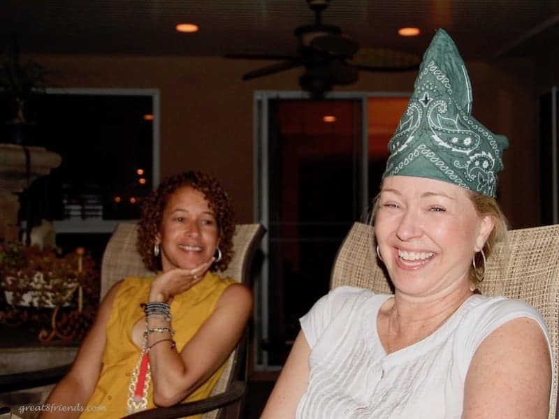 Two woman smiling while one is wearing a green bandana on her head.