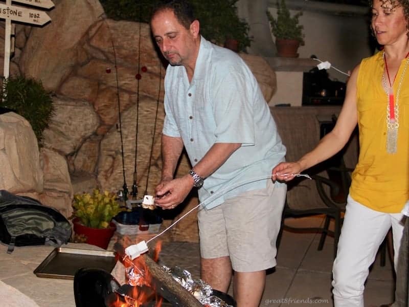 A man and a woman roasting homemade marshmallows over a fire.