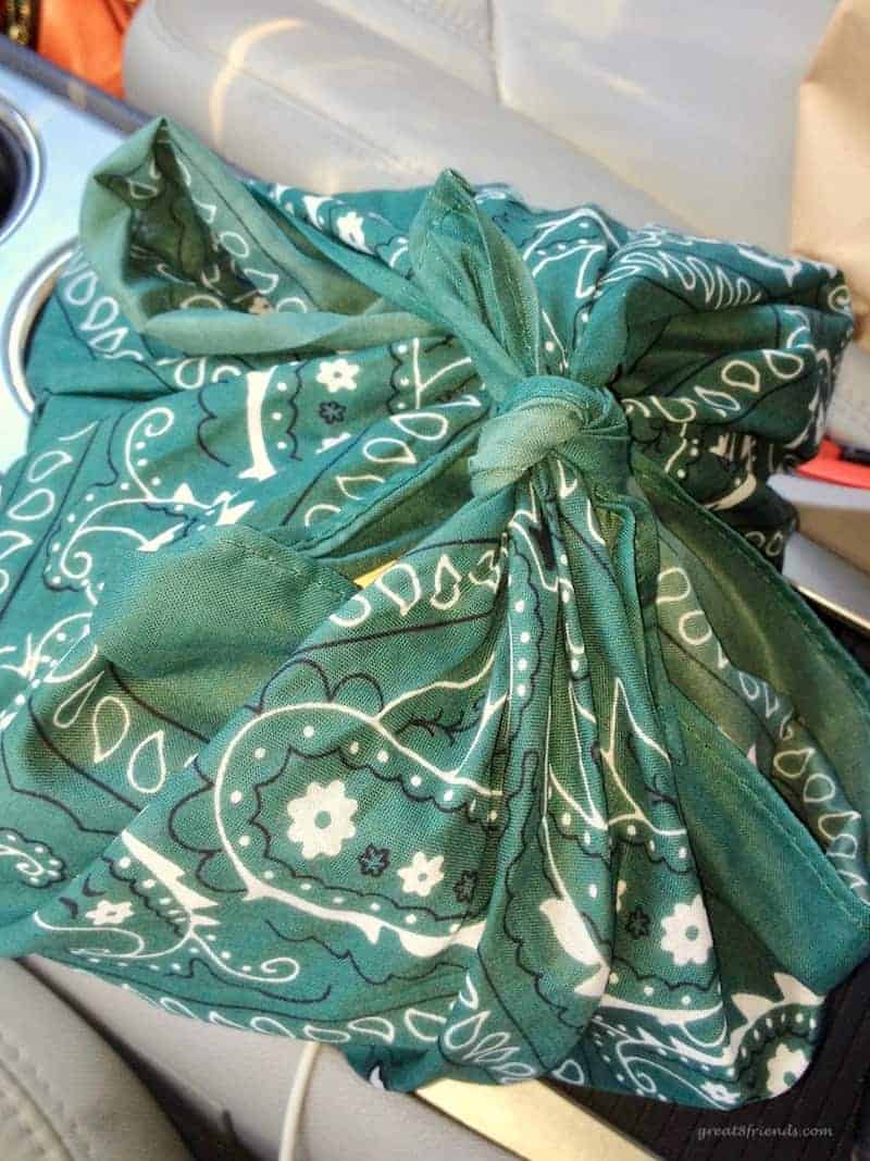 A green bandana tied with the camping themed dinner party invitation inside.