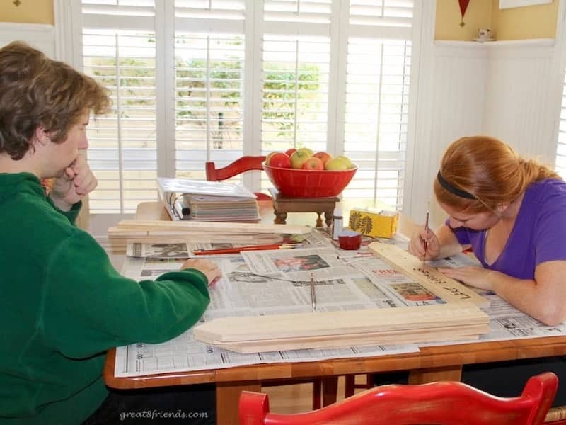 A young boy and girl working on signs for the camping themed dinner party.