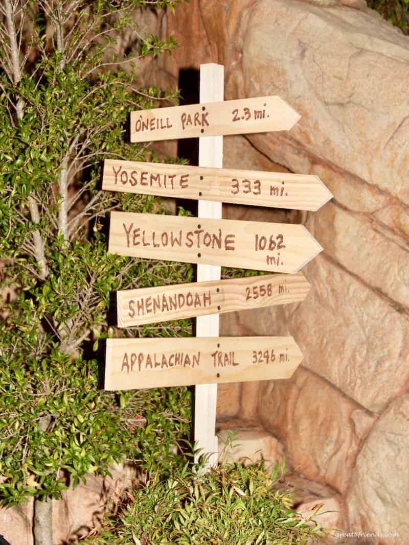 A handmade wooden sign indicating direction for a camping themed dinner party.