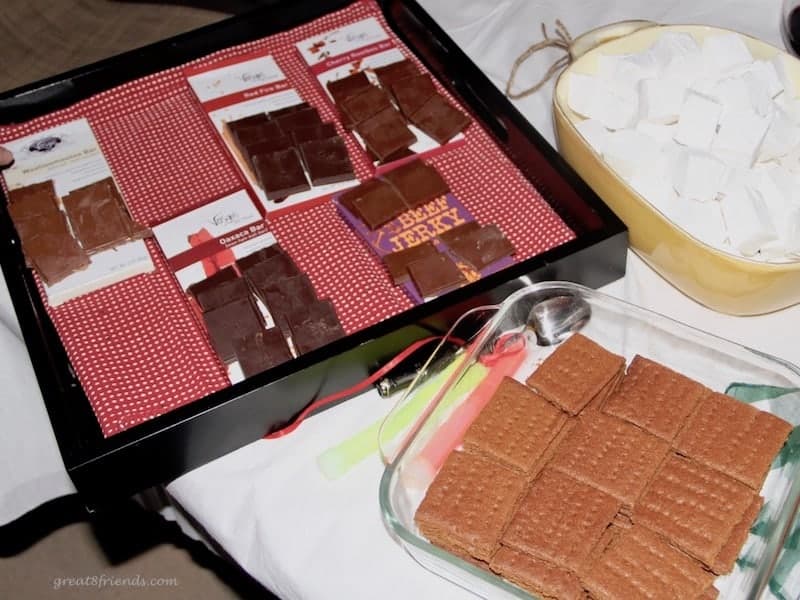 Gourmet chocolate on a tray with homemade graham crackers in a glass serving dish and homemade marshmallows in a yellow baking dish.