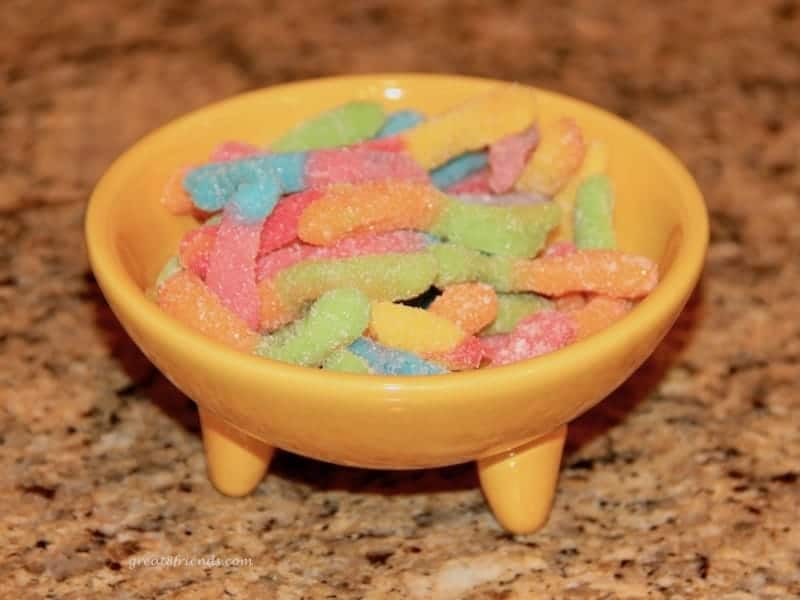 Colorful gummy worms in a yellow bowl.