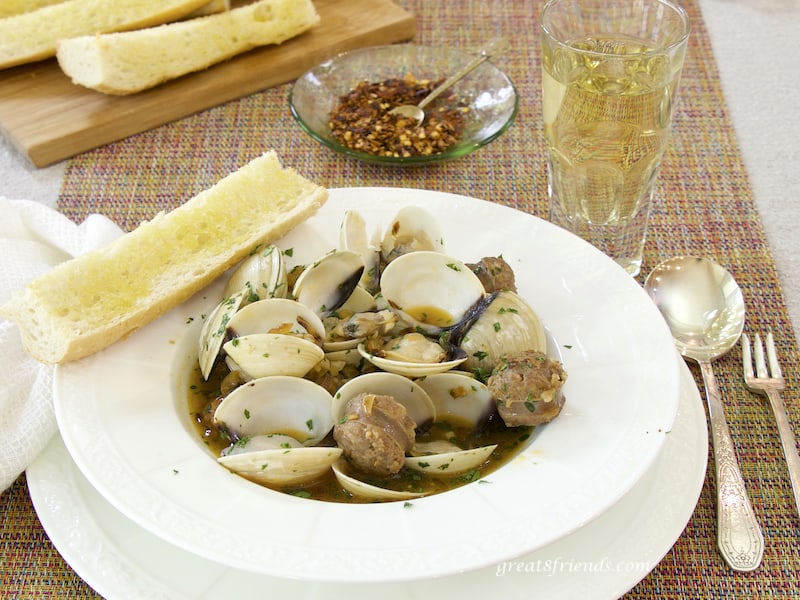 Clams with Hot Italian Sausage in bowl with bread, hot pepper, white wine and spoon