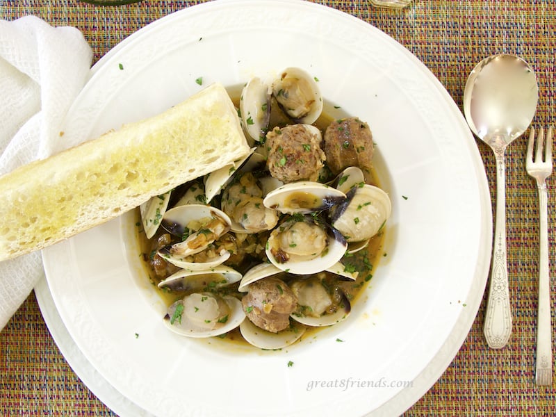 Overhead shot of Clams with Hot Italian Sausage in bowl with bread and spoon