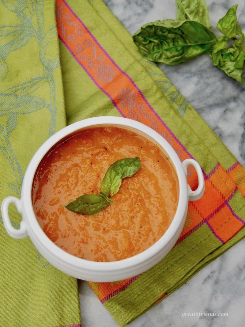 Overhead view of Roasted Carrot and Tomato Soup with a basil garnish.