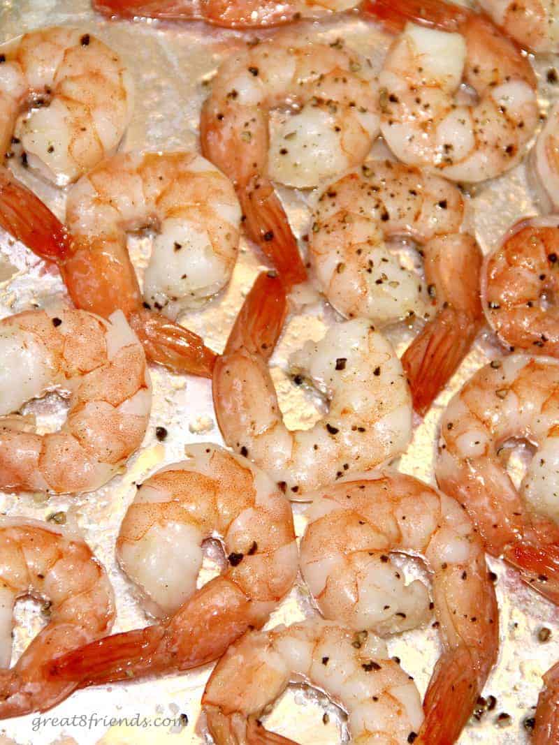 Unclose photo of cooked shrimp on a baking sheet seasoned with pepper.