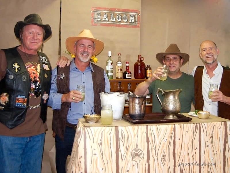 Four men in western wear standing at a bar.