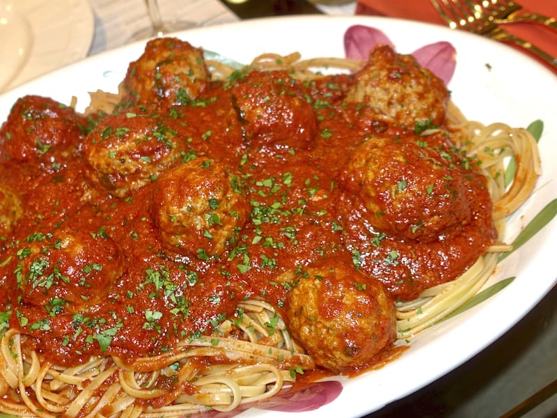 A platter of spaghetti and meatballs with parsley sprinkled on top.