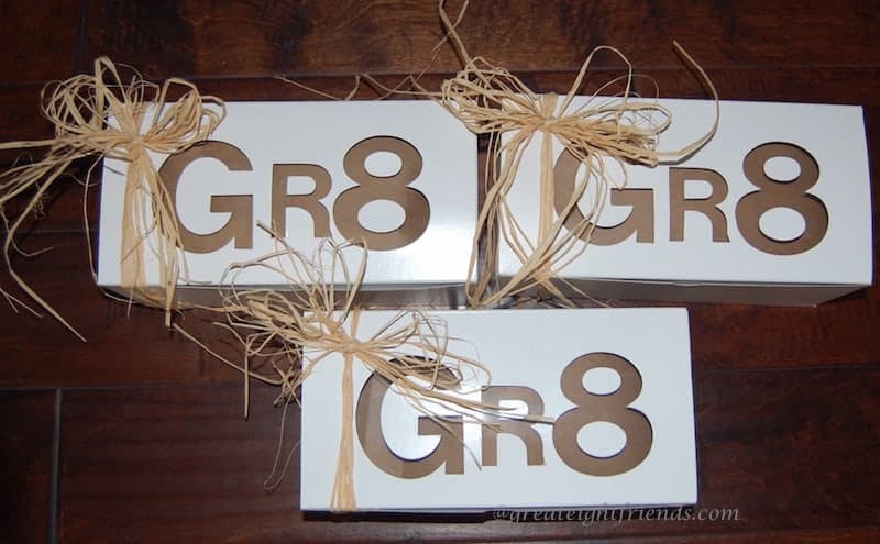 Three white boxes with 'Gr8' cut out on the top decorated with a straw bow.