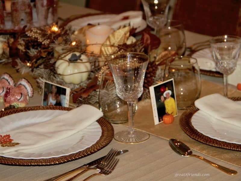 A Friendsgiving table setting with a photo next to the plate of the guest assigned to sit in that place.
