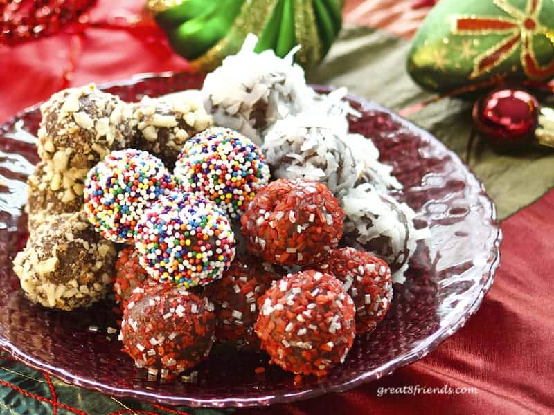 Chocolate truffles on red glass plate with Christmas decorations.