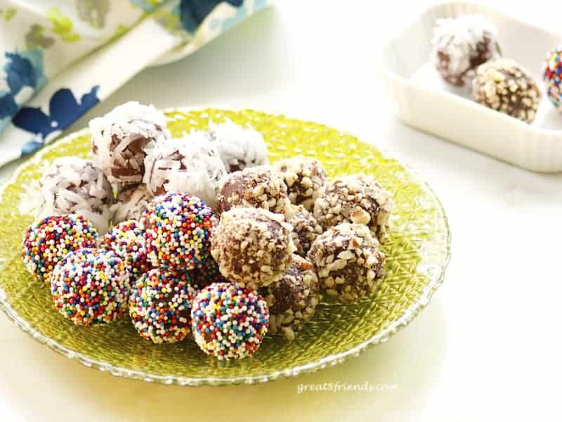 Assorted chocolate truffles on green glass plate.