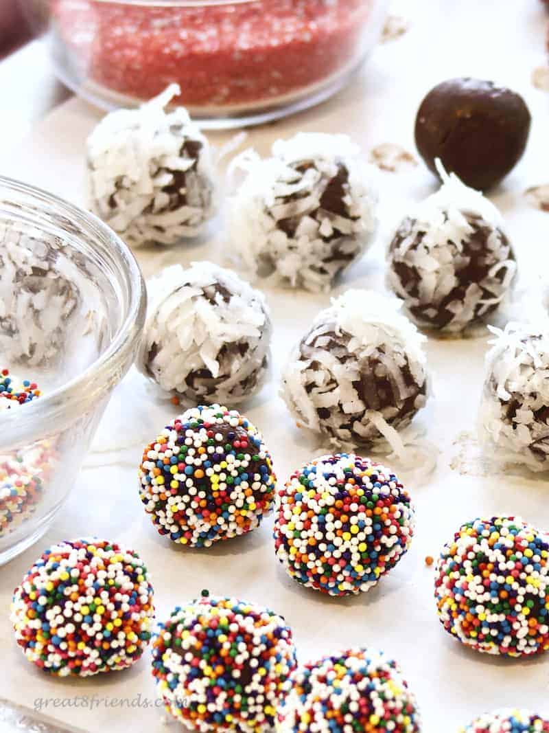 Truffles being rolled in candy and cocounut.