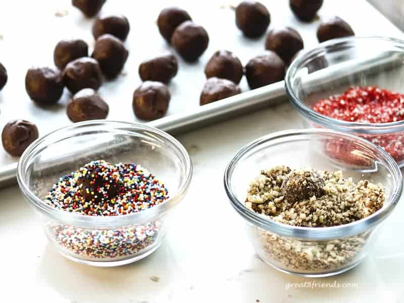 Chocolates being rolled in candy and nut toppings.