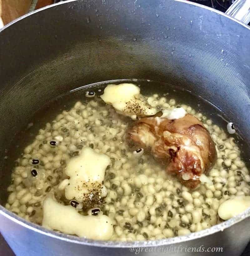 A pot simmering with a ham hock and peas in the water.