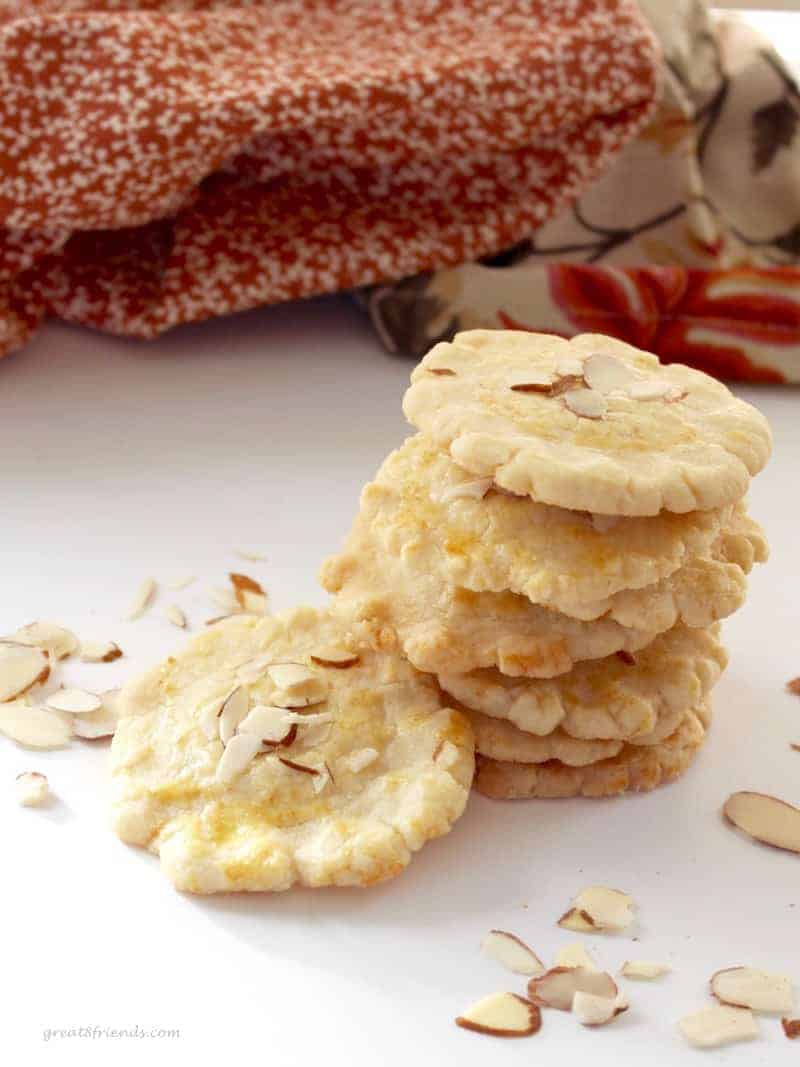 A stack of Almond Cookies with sliced almonds sprinkled around.