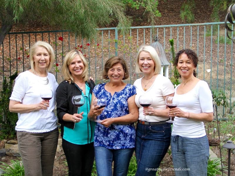 Five ladies drinking wine in the yard.