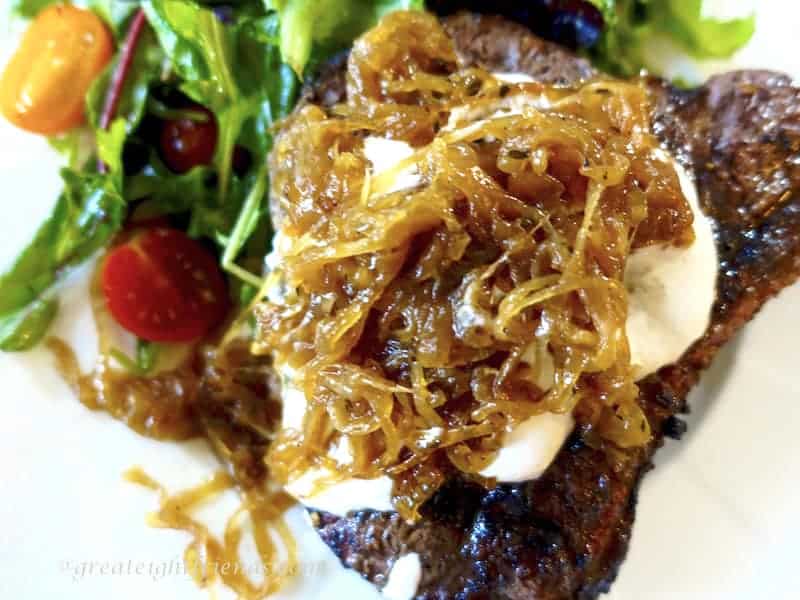 Caramelized Onion Jam on top of a steak with salad on the side.