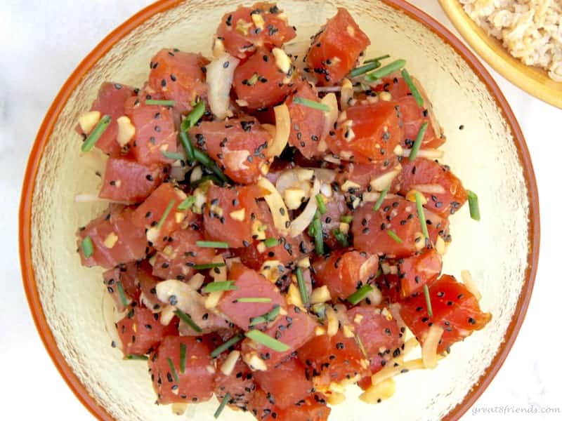 A yellow glass bowl with fresh ahi poke tossed with other ingredients.