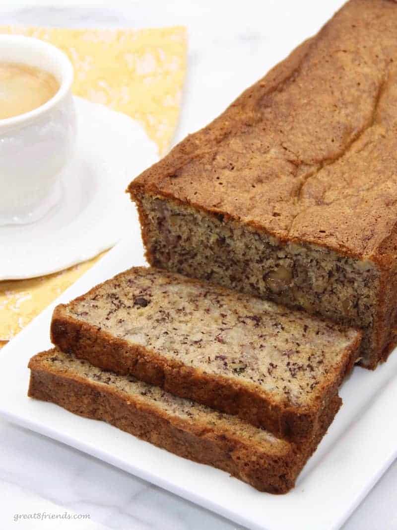 Banana bread loaf on a rectangular white plate with two pieces sliced.