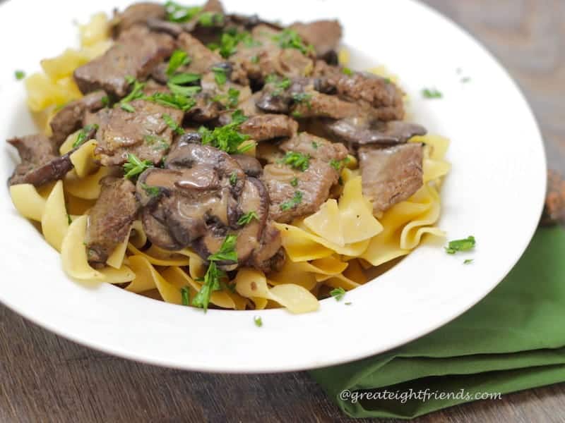 Beef Stroganoff over noodles in a white bowl.