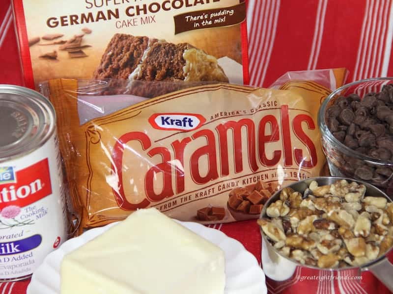 Ingredients to make brownies including cake mix, chocolate chips, bag of caramels, evaporated milk, butter and nuts.