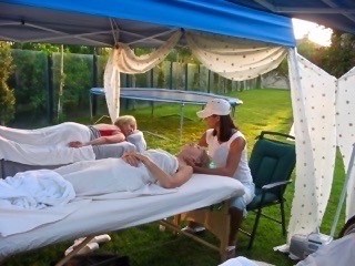 A woman getting a massage outside under a blue canopy.