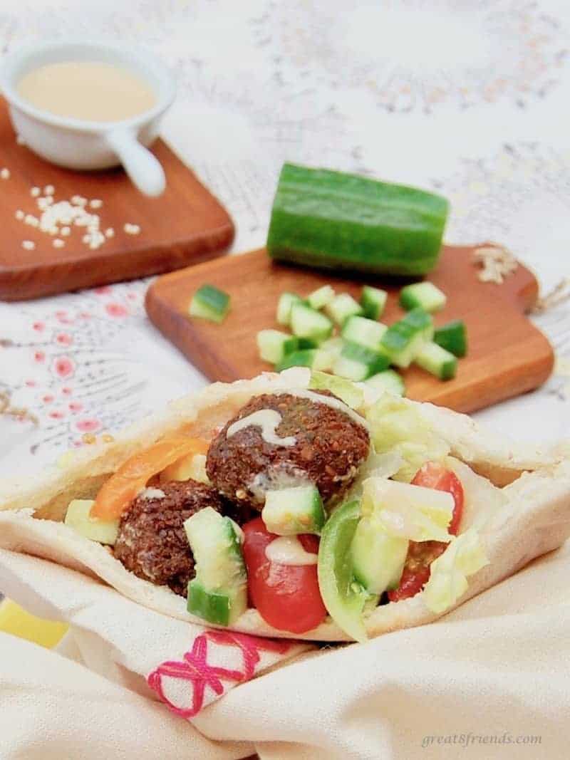 A Falafels served in a pita with chopped cucumber and tomatoes with tahini on the side.