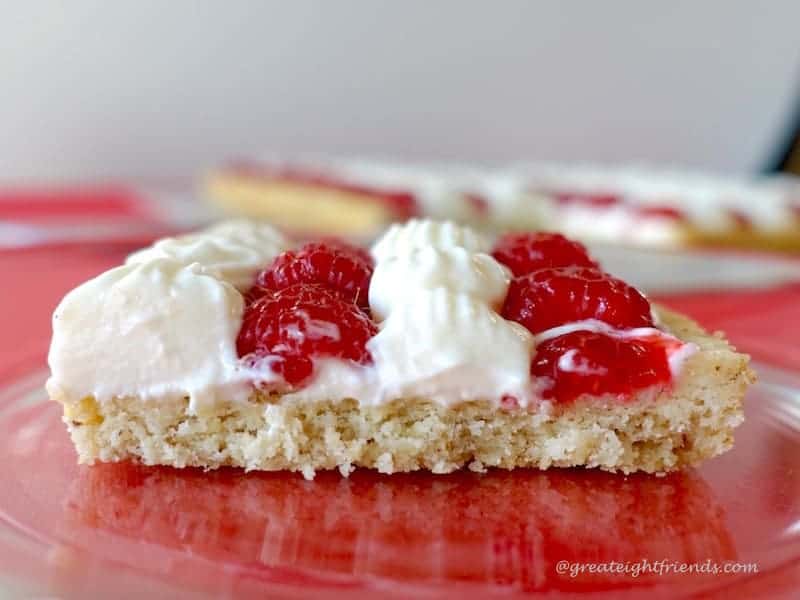 A side view of a slice of fruit pizza with raspberries and the cheesecake mousse.