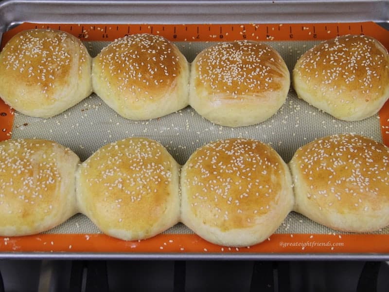 Baked homemade hamburger buns with sesame seeds on baking sheet