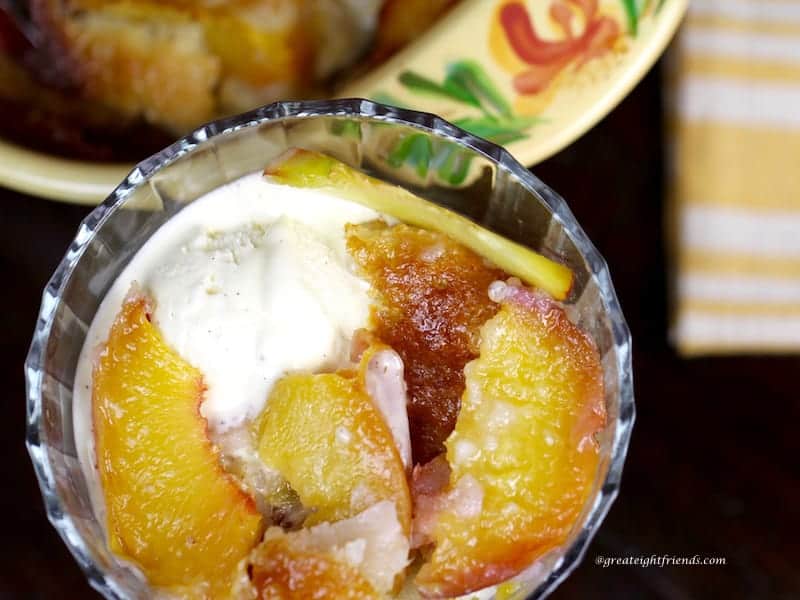 Unclose overhead view of peach cobbler with vanilla ice cream served in a glass round dish.