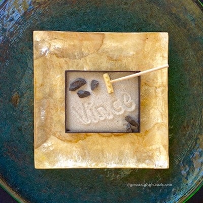 A mini zen garden with the name Vince written in the sand.