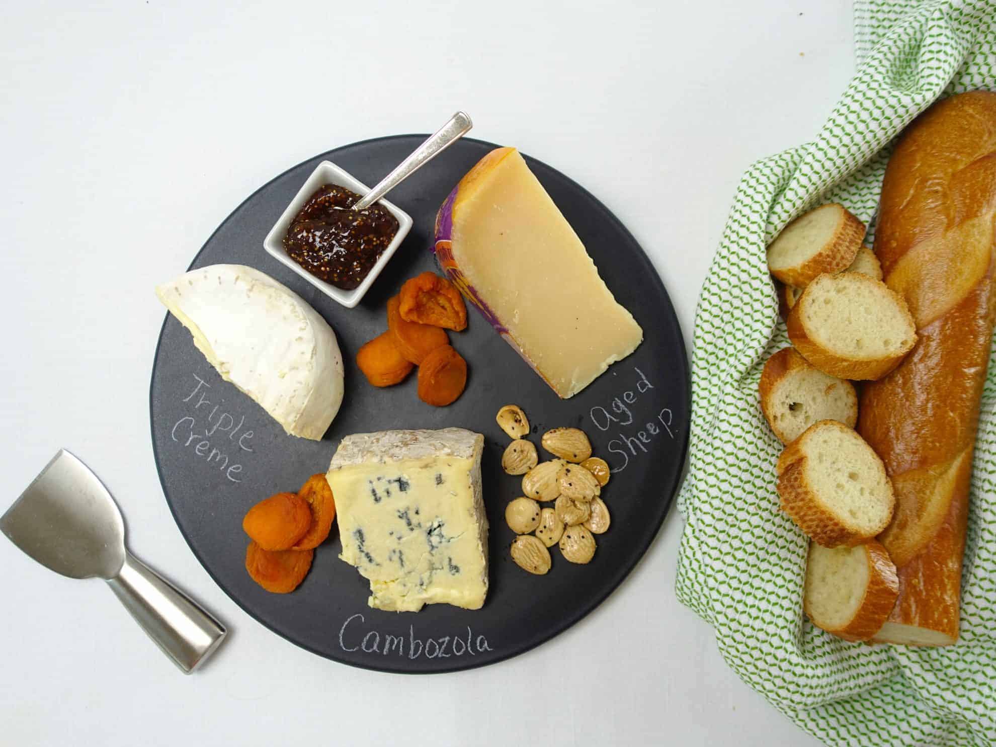 A Cheese and Charcuterie Board with apricots, fig jam, almonds and bread slices.