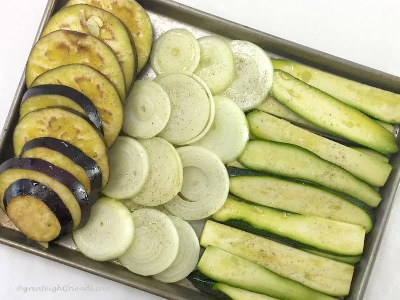 eggplant, onions and zucchini sliced on a pan awaiting the grill.