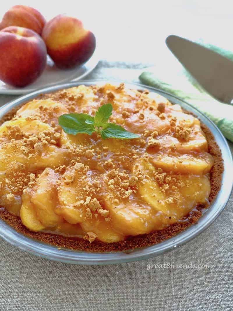 Peach Amaretti Pie with some fresh peaches in the background.