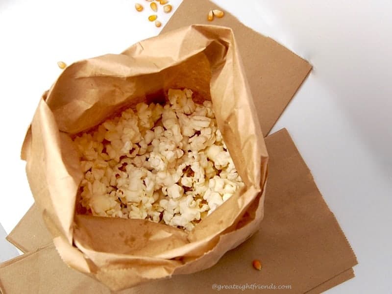 A brown paper bag filled with popped popcorn.